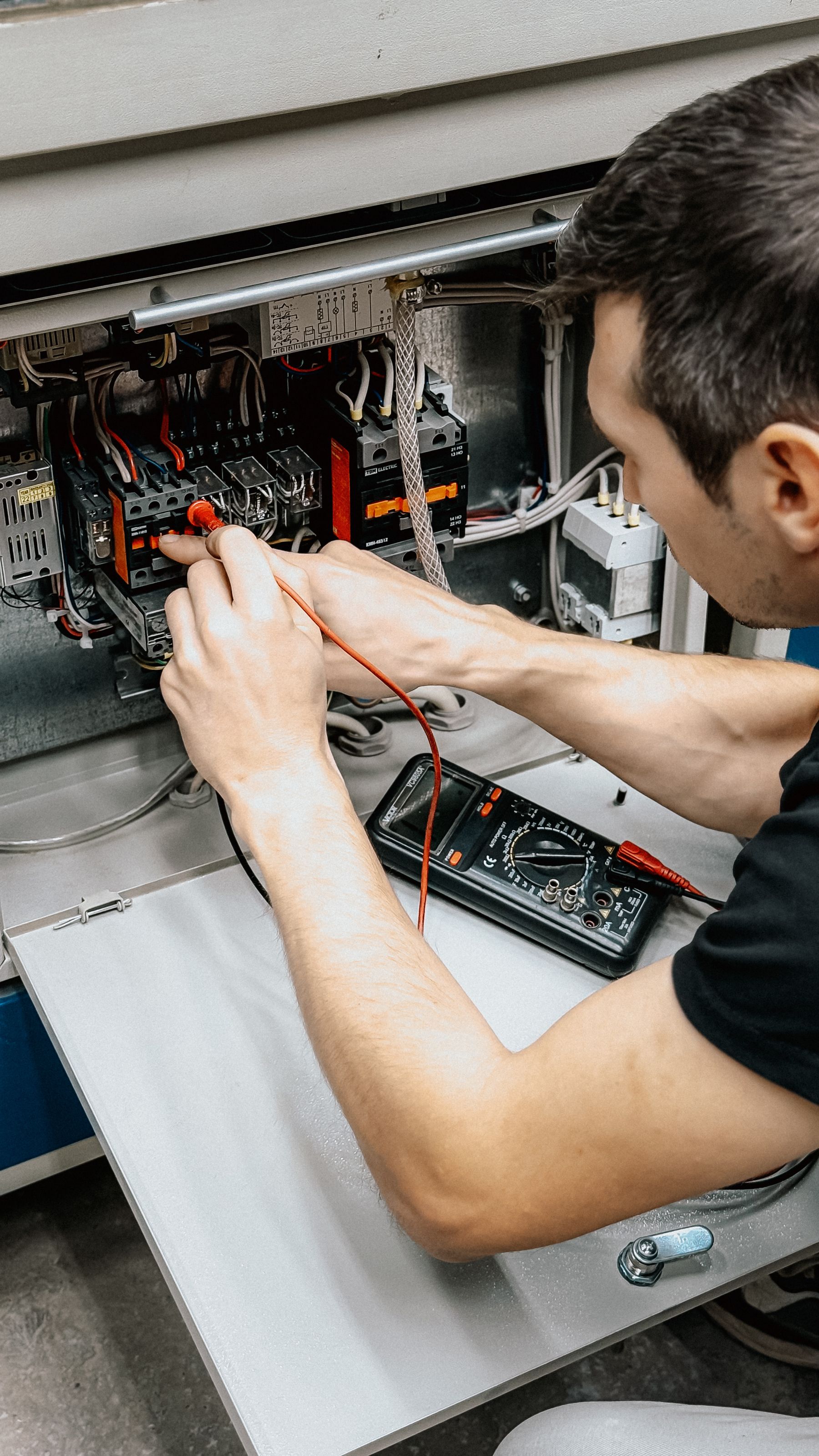 Technician testing an industrial electrical control panel